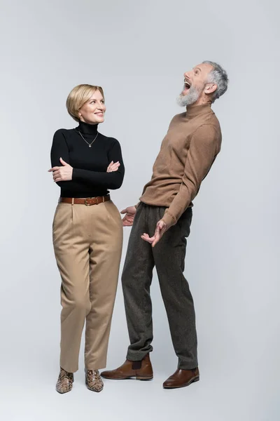 Aufgeregt reifer Mann steht neben stilvoller Frau auf grauem Hintergrund — Stockfoto