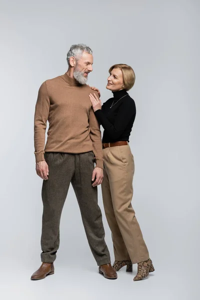 Blonde Frau berührt stilvollen reifen Mann auf grauem Hintergrund — Stockfoto