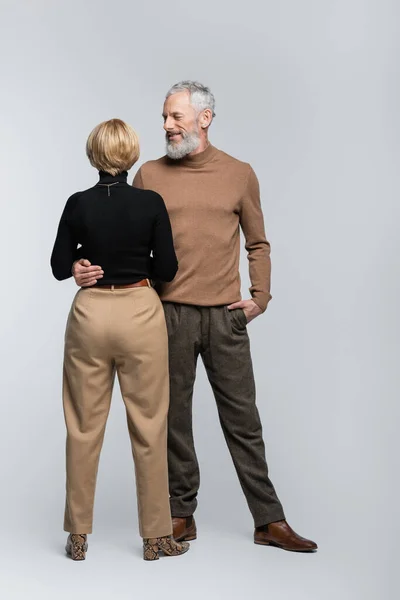 Smiling mature man hugging blonde wife on grey background — Stock Photo