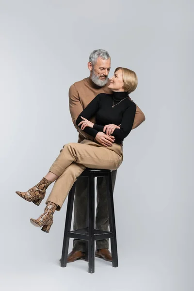 Happy mature couple hugging and looking at each other on grey background — Stock Photo