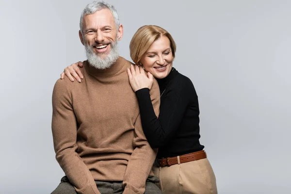 Blonde woman in turtleneck hugging mature husband isolated on grey — Stock Photo