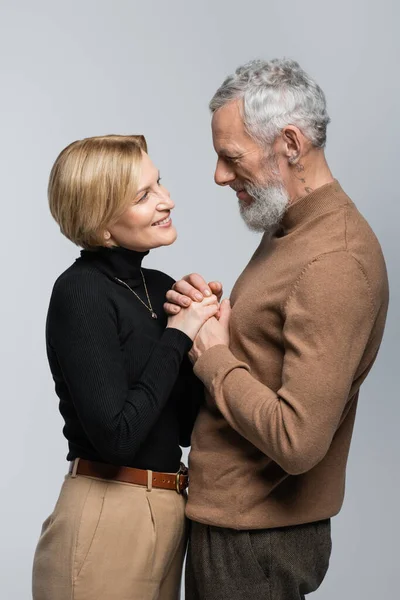Cheerful mature and stylish couple holding hands isolated on grey — Stock Photo