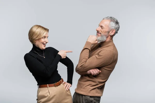 Positive reife Frau zeigt auf stilvollen Ehemann isoliert auf grau — Stockfoto