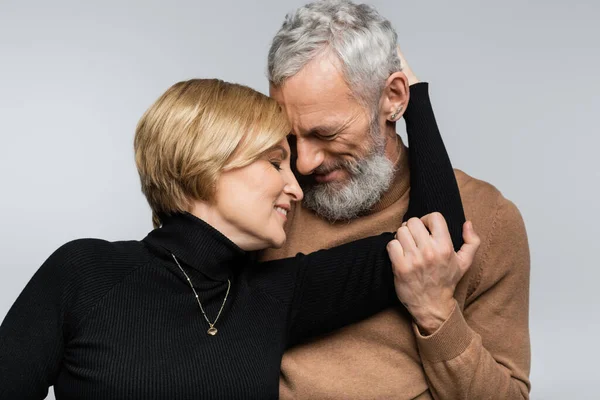 Portrait of mature woman hugging grey haired husband isolated on grey — Stock Photo