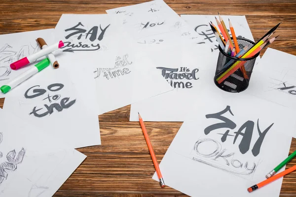 Papers with different words and phrases, felt pens and color pencils on wooden desk — Stock Photo