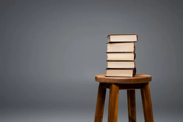 Taburete de madera con pila de libros aislados en gris - foto de stock