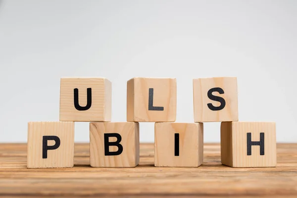 Stack of cubes with black publish inscription on wooden surface isolated on grey — Stock Photo