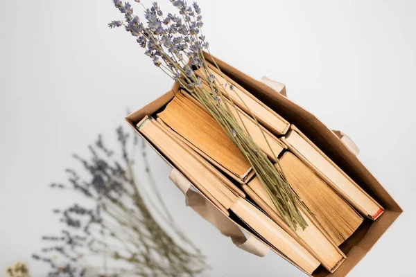 Top view of shopping bag with books and lavender flowers isolated on grey — Stock Photo