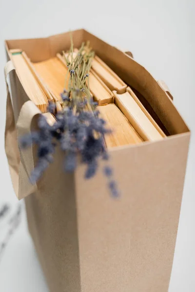 Sac à provisions avec livres et fleurs de lavande floues isolées sur gris — Photo de stock