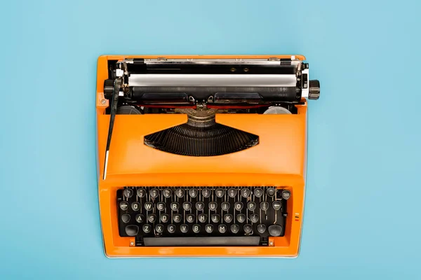 Vista superior de la máquina de escribir naranja con teclado negro aislado en azul - foto de stock