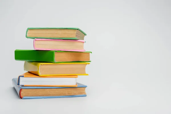 Stacked books with multicolored covers on grey background — Stock Photo