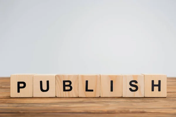 Wooden cubes with publish lettering on brown surface isolated on grey — Stock Photo