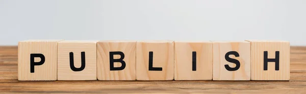 Row of wooden cubes with word publish isolated on grey, banner — Stock Photo