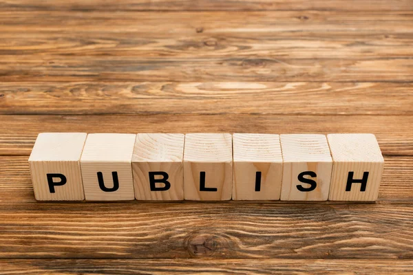 Wooden cubes with black publish inscription on textured desk with copy space — Stock Photo