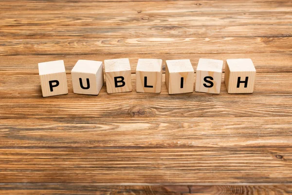 Line of wooden cubes with word publish on brown textured surface — Stock Photo