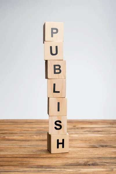 Stack of cubes with publish lettering on wooden surface isolated on grey — Stock Photo