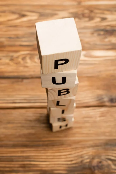 Stacked cubes with word publish on blurred wooden surface — Stock Photo