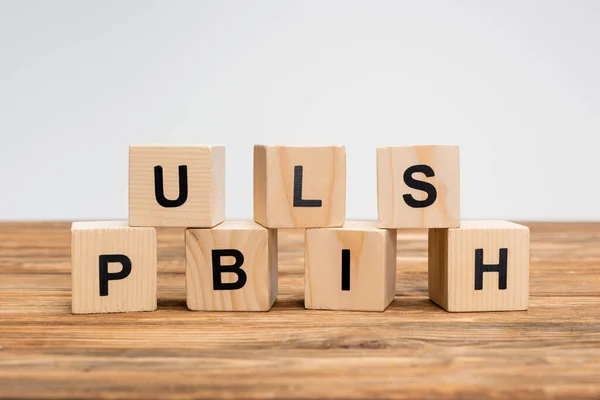 Word publish on wooden cubes and brown surface isolated on grey — Stock Photo