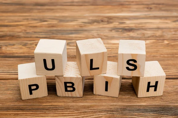 Close up view of wooden cubes with black publish inscription on wooden desk — Stock Photo