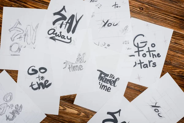 Top view of white papers with various words and phrases on wooden desk — Stock Photo