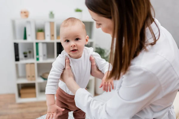 Blurred family doctor holding baby boy in hospital — Stock Photo