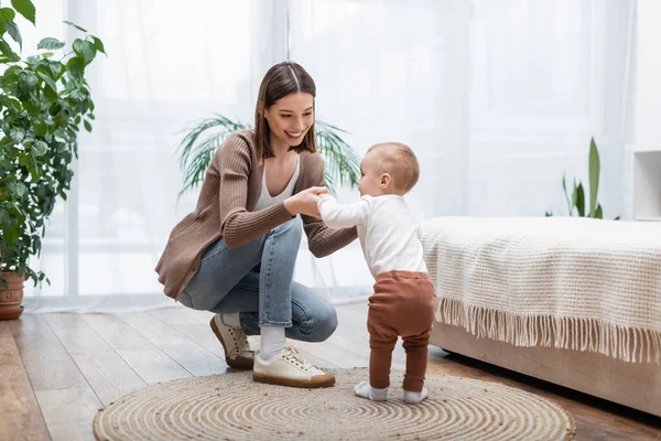 Junge Eltern halten Hand von Säugling auf Teppich im Schlafzimmer — Stockfoto