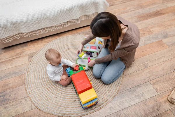 Overhead view of parent holding building blocks near son with pacifier at home — Stock Photo