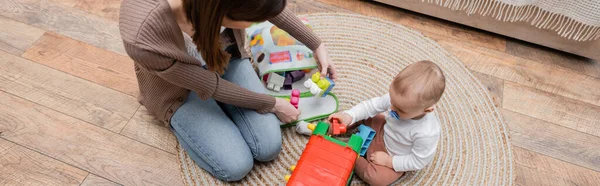 Overhead view of mom holding building blocks near baby son at home, banner — Stock Photo