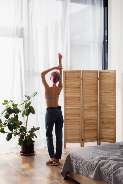 Back view of young woman with dyed hair standing near folding screen — Stock Photo