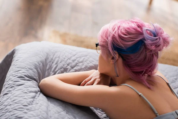 Vista de ángulo alto de la mujer joven con el pelo teñido acostado en la cama - foto de stock