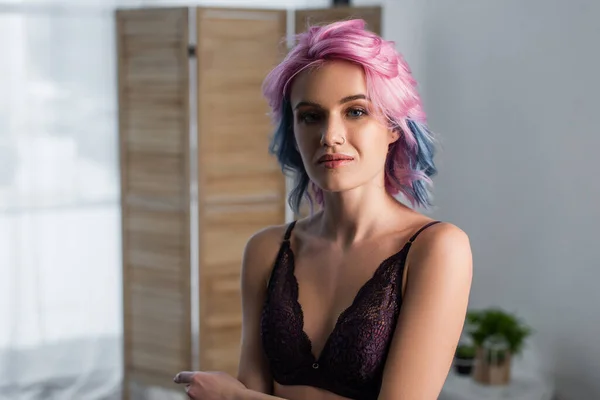 Sexy Frau mit gefärbten Haaren in dunklem SpitzenbH blickt in die Kamera — Stockfoto