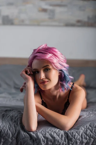 Портрет молодой женщины в сексуальном белье, смотрящей в камеру и лежащей на кровати — стоковое фото