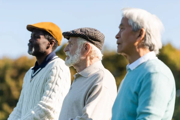 Senior man in flat cap near interracial friends — Stock Photo