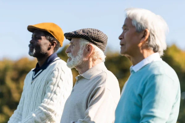 Senior mit Schiebermütze in der Nähe von Freunden — Stockfoto