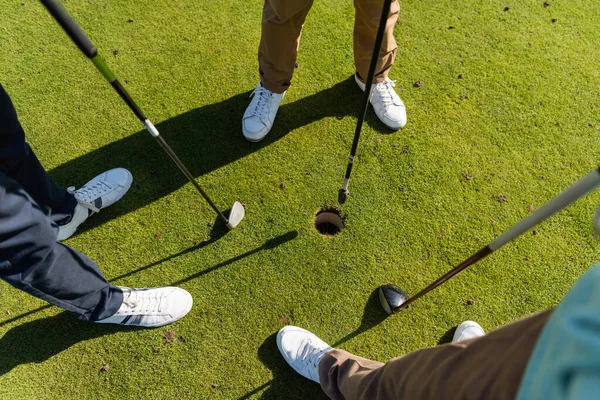 High angle view of senior friends standing with golf clubs on lawn — стоковое фото