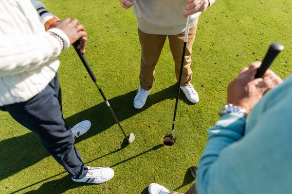 Vue grand angle de interracial amis aînés debout avec des clubs de golf sur la pelouse — Photo de stock