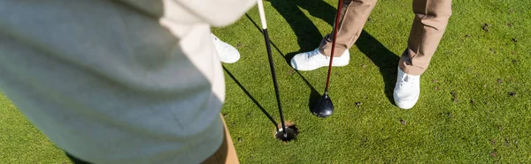 Cropped view of senior man holding flag stick near friend on golf field, banner — стоковое фото