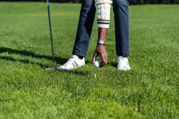 Cropped view of african american man placing ball on golf tee — Stock Photo