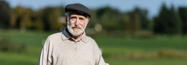 Senior man in flat cap looking at camera, banner — Stock Photo