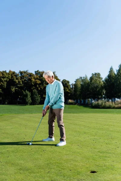 Asian senior man holding golf club while playing outdoors — Stock Photo