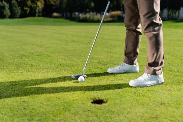 Vista cortada do homem em tênis brancos jogando golfe no gramado — Fotografia de Stock