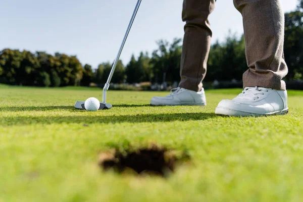 Частичный вид человека в белых кроссовках, играющего в гольф на газоне — стоковое фото