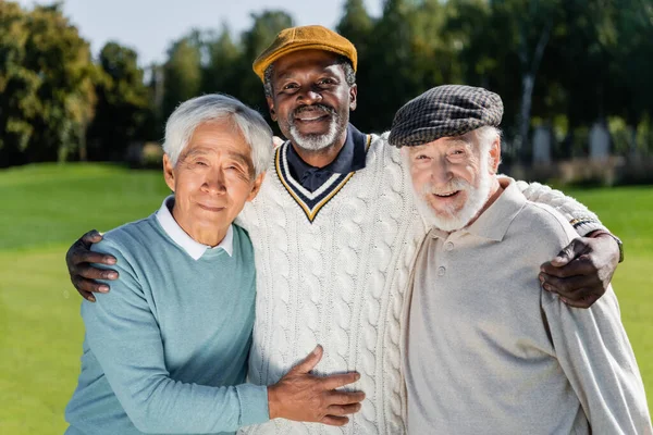 Felices y mayores amigos interracial mirando a la cámara - foto de stock