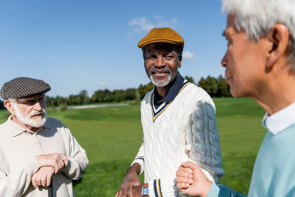 Senior multiethnic men looking at blurred asian friend — стоковое фото