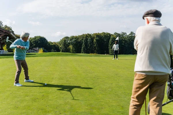 Senior asiático hombre jugando golf con interracial amigos - foto de stock