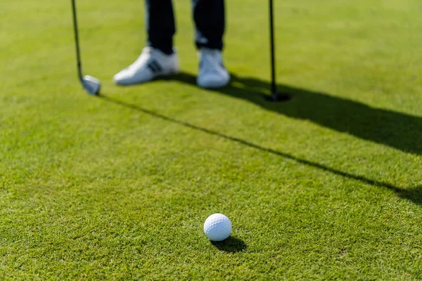 Golf ball on green lawn near blurred man — Stock Photo