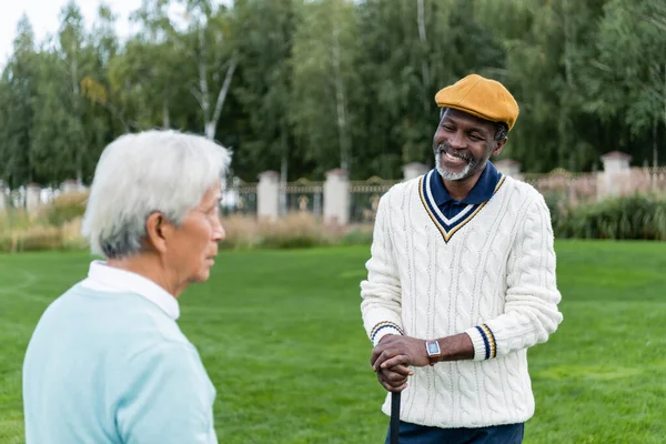 Sorridente africano americano homem olhando para sênior asiático amigo — Fotografia de Stock