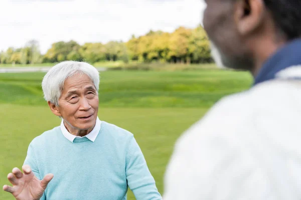 Senior asiatico uomo guardando offuscata africano americano amico — Foto stock
