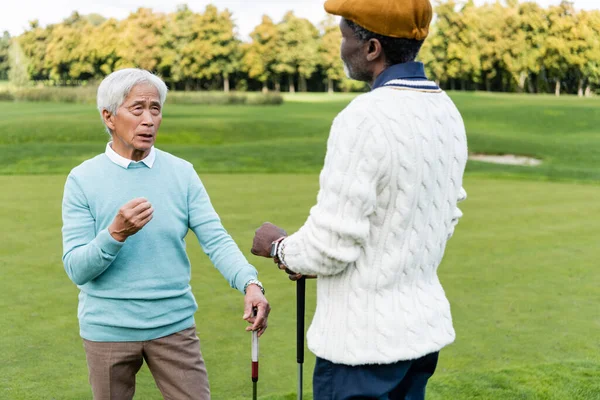 Senior asiatische Mann im Gespräch mit afrikanisch-amerikanischen Freund in Schiebermütze — Stockfoto