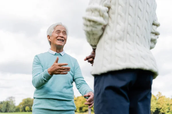 Low angle view of happy senior asian man talking with african american friend — Stock Photo